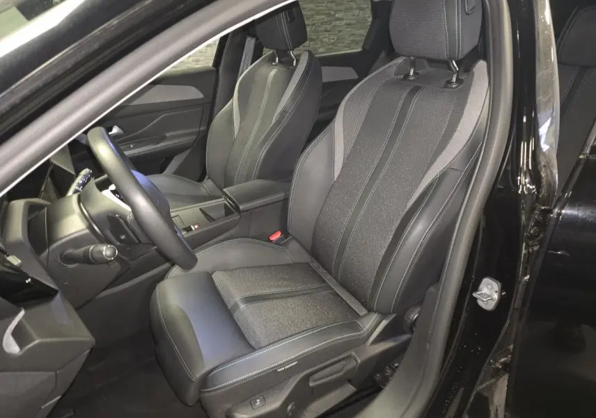 Intérieur Peugeot 308 SW noir, vue côté conducteur sur siège avant en tissu et cuir avec surpiqûres bleues.