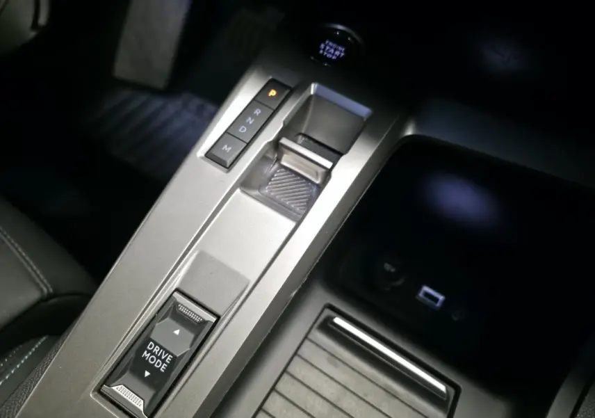 Gros plan sur la console centrale grise avec sélecteur de boîte auto et bouton Drive Mode de la Peugeot 308 SW noire.