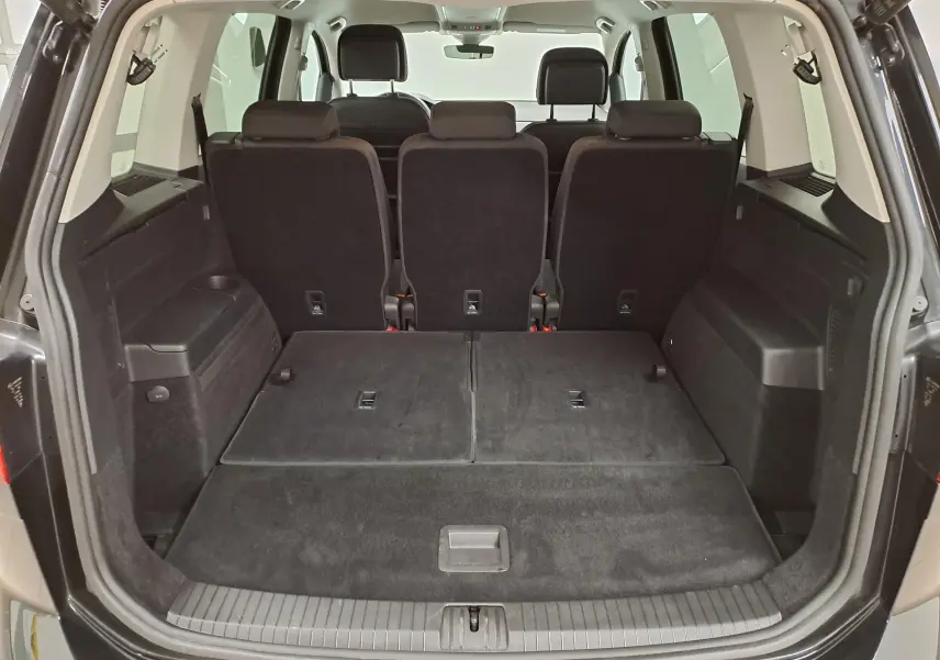 Vue arrière du coffre ouvert du Volkswagen Touran noir intense nacré, montrant les sièges arrière et l'espace de chargement.