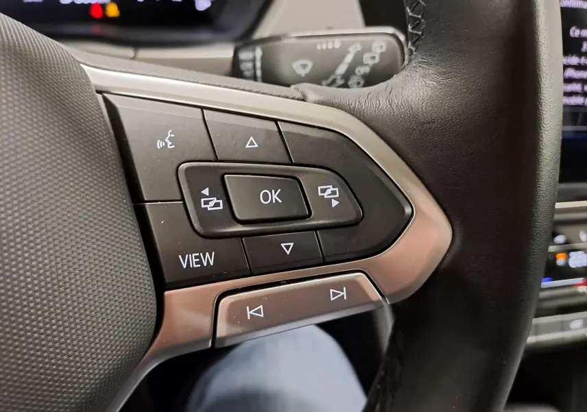 Gros plan sur les commandes au volant côté gauche du Volkswagen Touran 2025, finition VW Edition, avec cuir noir.