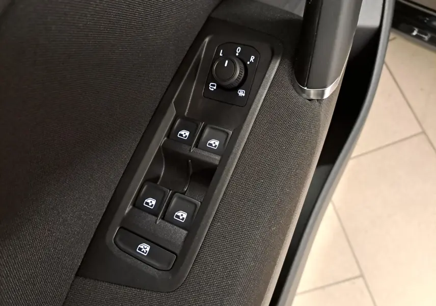 Gros plan sur les commandes de lève-vitres et rétroviseurs côté gauche intérieur du Volkswagen Touran noir intense nacré 2025.