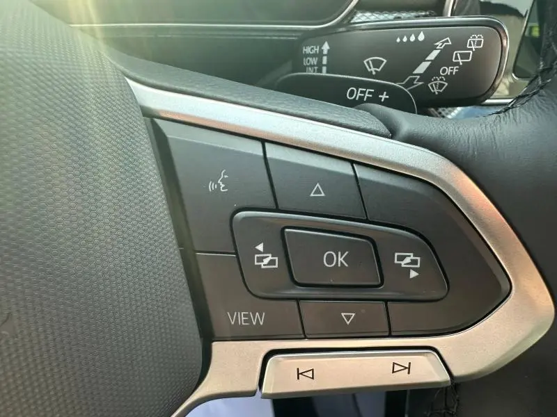 Gros plan sur les commandes du volant du Volkswagen T-Cross 2025 R-Line, avec finition argentée et boutons multifonctions.