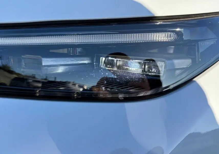 Gros plan sur le phare avant droit du Citroën C5 Aircross blanc Okenite, mettant en valeur les détails LED et la signature lumineuse.