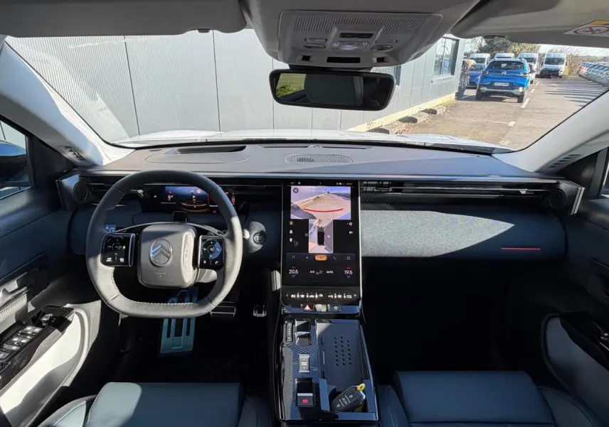 Vue intérieure avant du Citroën C5 Aircross blanc Okenite, tableau de bord moderne avec écran tactile vertical et volant multifonctions.