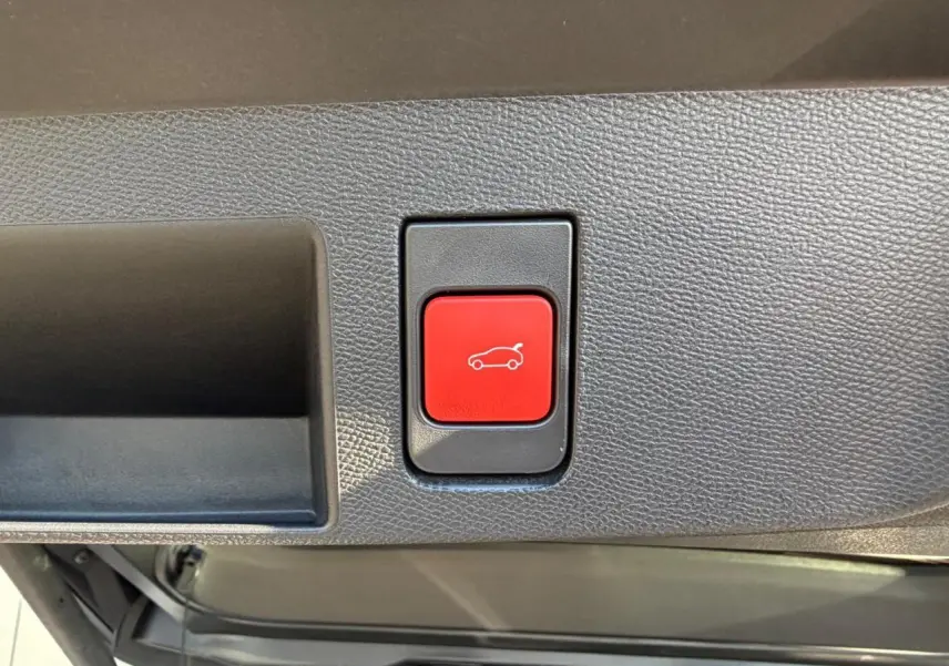 Gros plan sur le bouton rouge d'ouverture électrique du hayon dans le coffre du Citroën C5 Aircross blanc.