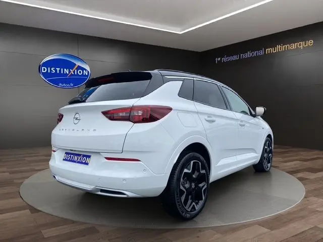 Opel Grandland blanc Arktis avec toit noir, vue 3/4 arrière droit, jantes alliage noires et feux LED distinctifs.