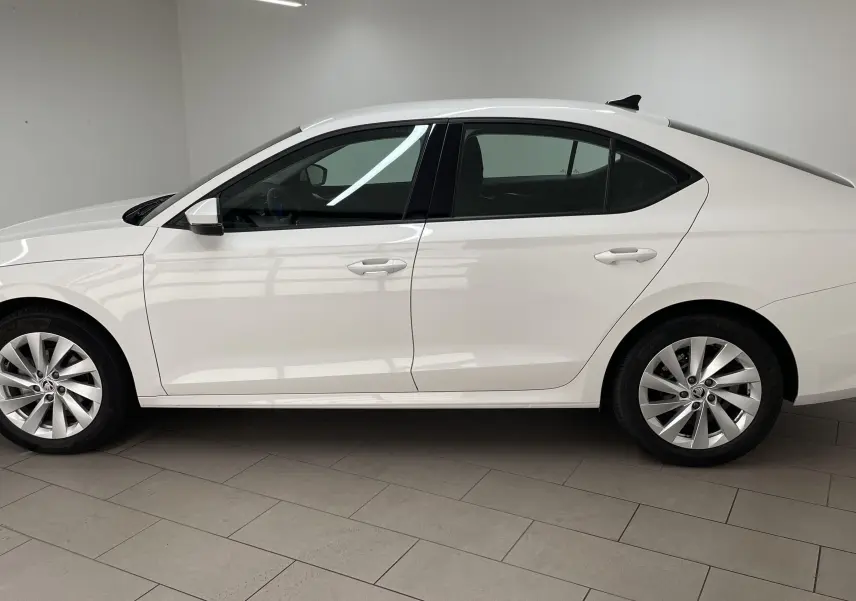 Profil côté gauche d'une Skoda Octavia blanc candy 2024 avec jantes alliage et feux arrière allumés.