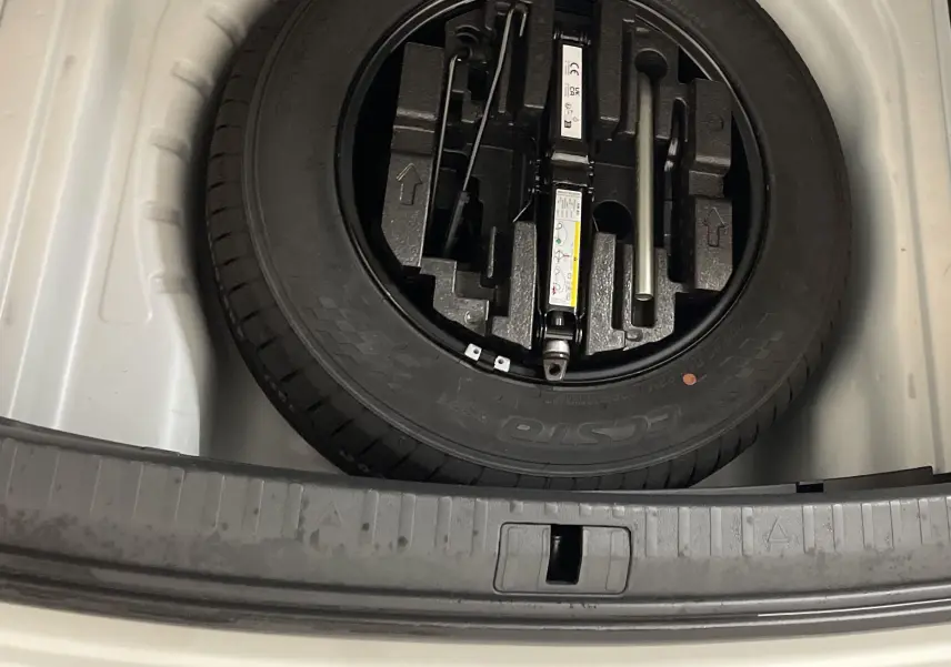 Gros plan sur la roue de secours galette noire dans le coffre blanc d’une Skoda Octavia 2024 2.0 TDI DSG7.