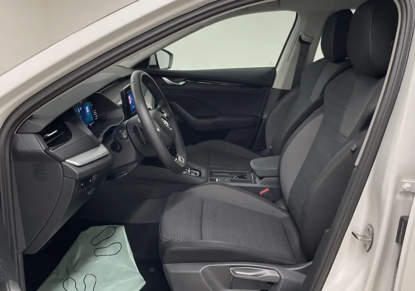 Intérieur côté conducteur de la Skoda Octavia 2024 blanc candy, sièges noirs et tableau de bord moderne avec écran tactile.