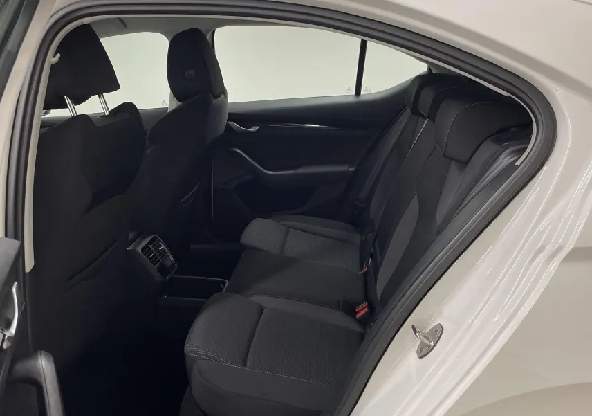 Vue intérieure côté droit arrière de la Skoda Octavia 2024 blanc candy, montrant les sièges arrière noirs et la portière ouverte.
