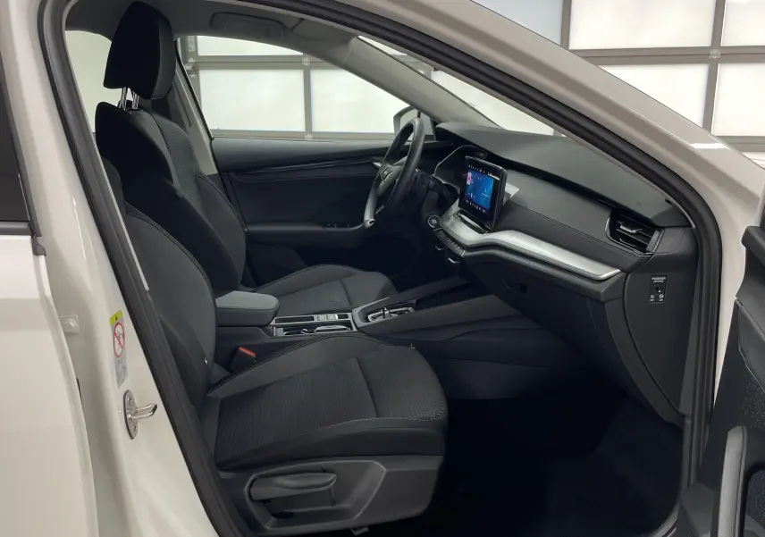 Intérieur avant droit de la Skoda Octavia 2024 blanc candy, sièges noirs et tableau de bord moderne avec écran tactile.