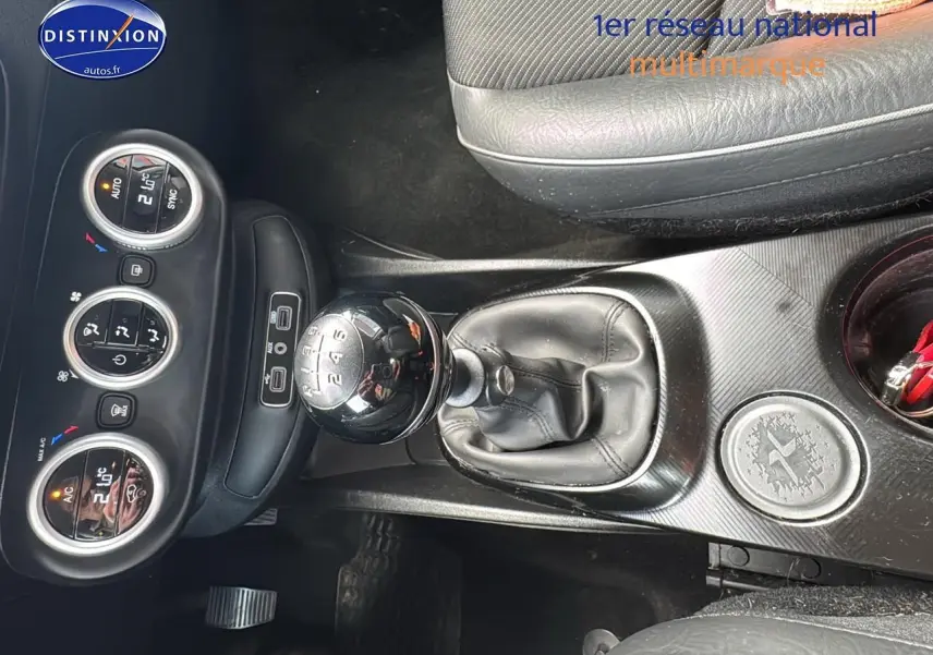 Vue rapprochée de la console centrale de la Fiat 500X rouge, mettant en valeur le levier de vitesse manuel et les commandes de climatisation.