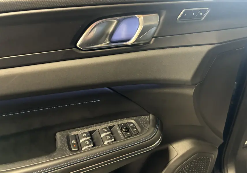 Intérieur côté gauche de la porte LYNK & CO 01 bleu, avec commandes de vitres, poignée et boutons mémoire siège.