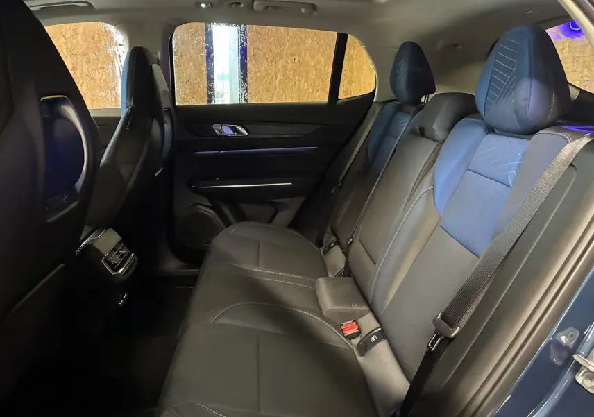 Vue latérale intérieure arrière du LYNK & CO 01 bleu, montrant les sièges arrière en cuir noir et bleu avec ceinture de sécurité.