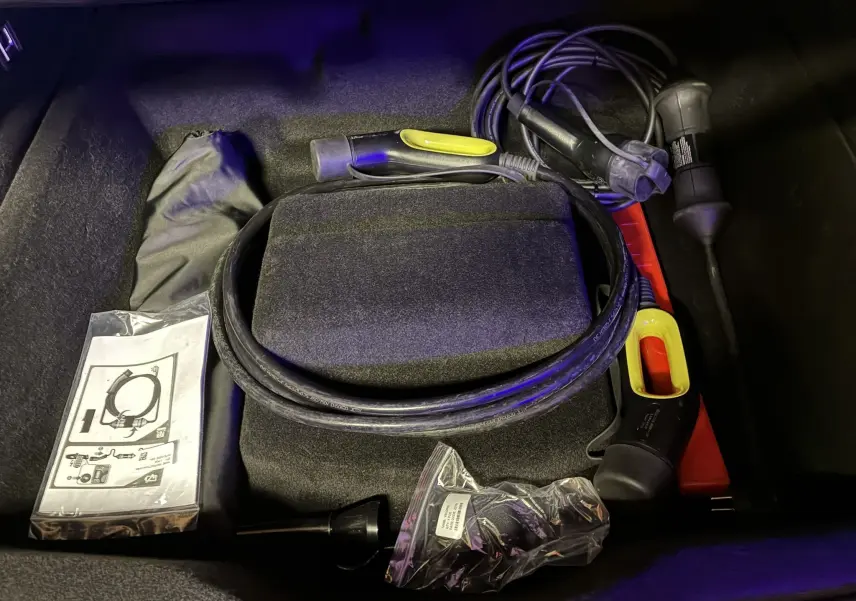 Coffre du Lynk & Co 01 bleu 2023 montrant câble de recharge hybride et accessoires de charge rangés.