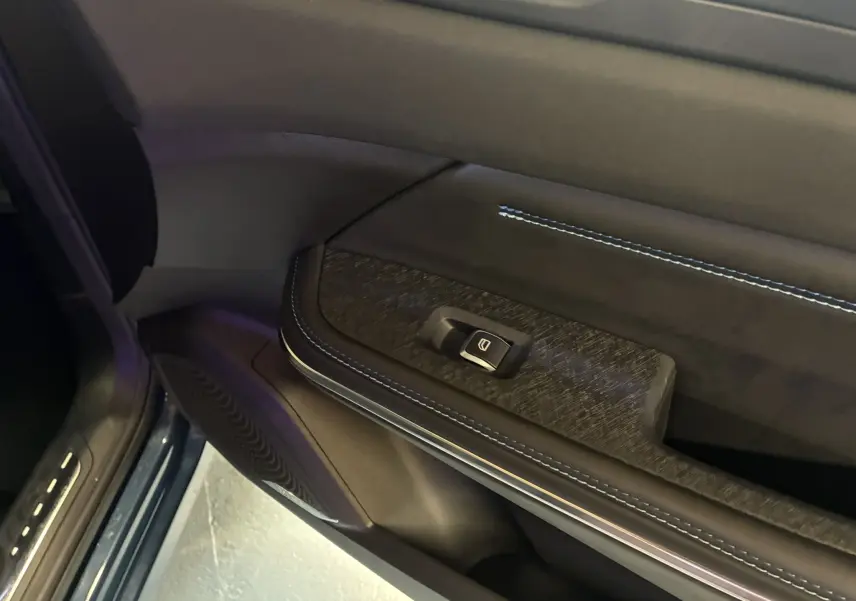 Détail de la portière côté gauche du LYNK & CO 01 bleu 2023, avec bouton de commande de vitre et surpiqûres bleues.