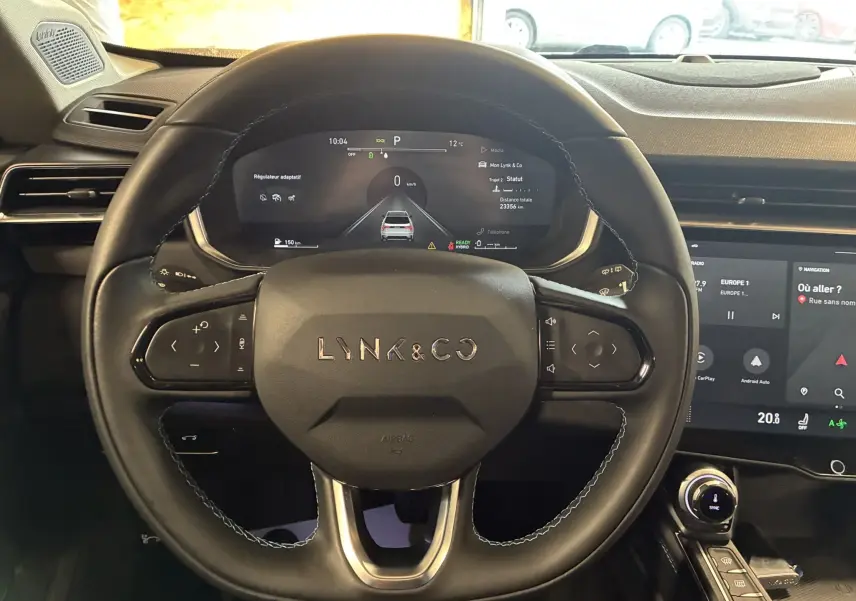 Vue rapprochée du volant noir du Lynk & Co 01 2023 avec tableau de bord digital et écran tactile central.