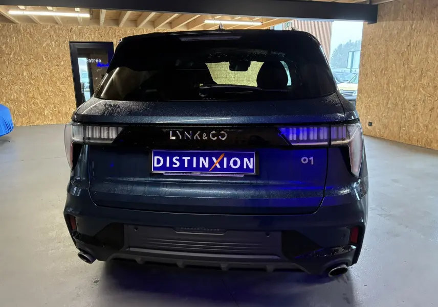 Vue arrière d'un SUV Lynk & Co 01 bleu 2023 avec feux arrière LED et double sortie d'échappement visible en intérieur.
