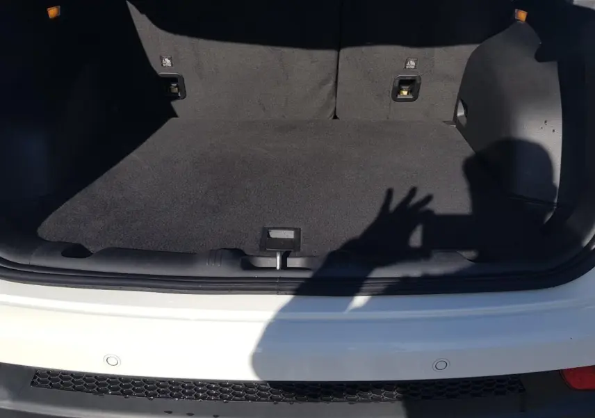 Coffre ouvert vu de l'arrière d'un Jeep Compass blanc 2024 avec intérieur noir et feux arrière rouges visibles.