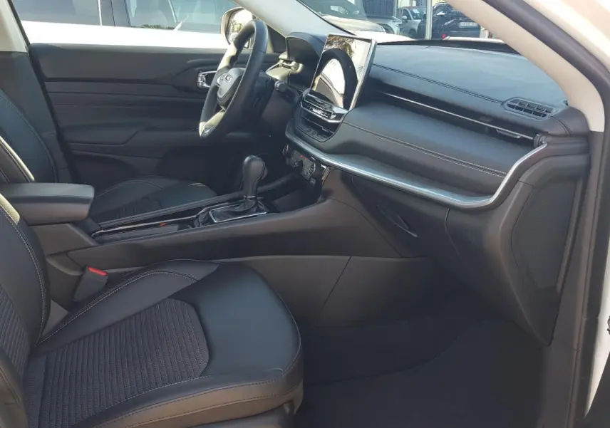 Vue intérieure côté conducteur du Jeep Compass blanc 2024, montrant siège noir, tableau de bord et écran tactile central.