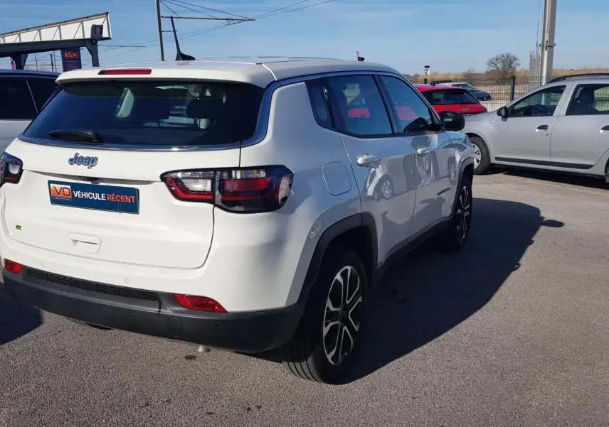 Jeep Compass blanc vu de 3/4 arrière droit, avec jantes alliage 18 pouces et feux arrière LED visibles.