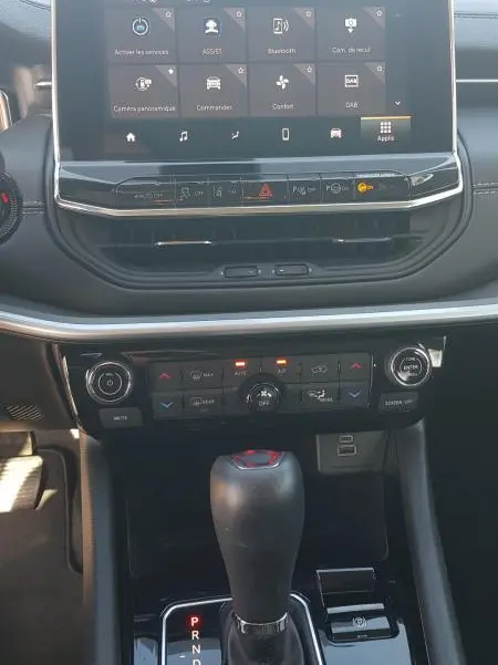 Vue rapprochée du tableau de bord et levier de vitesse du Jeep Compass blanc 2024 avec écran tactile et commandes climatisation.