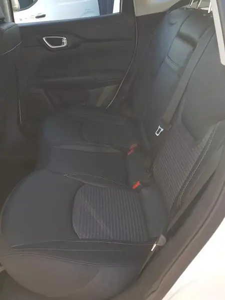 Vue intérieure du siège arrière droit du Jeep Compass blanc 2024 avec sellerie noire et ceinture de sécurité visible.