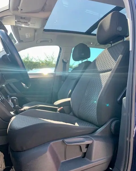 Intérieur du Volkswagen Tiguan 2018 bleu, vue côté gauche sur les sièges avant et toit panoramique lumineux.