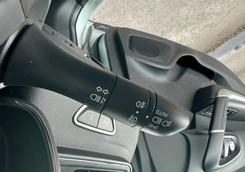Gros plan sur la commande des feux et clignotants à gauche du volant dans l'habitacle gris du Renault Kadjar.