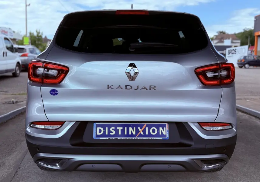 Vue arrière d'un Renault Kadjar gris avec feux rouges et plaque d'immatriculation Distinxion visible.
