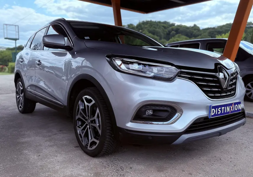 Renault Kadjar gris en 3/4 avant droit sous abri, avec calandre noire et jantes alliage distinctives.