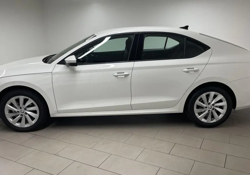 Profil côté gauche de la Skoda Octavia 2024 blanc candy, avec feux arrière allumés et jantes alliage visibles.