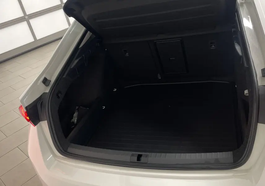 Coffre ouvert vu de l'arrière d'une Skoda Octavia blanc candy 2024 avec feu arrière droit allumé et roue de secours galette.