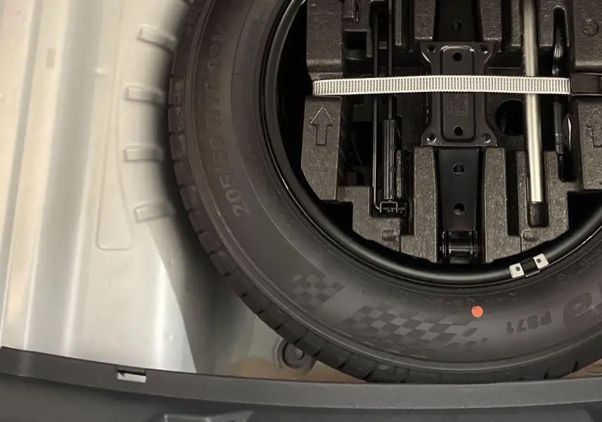 Gros plan sur la roue de secours galette noire dans le coffre d'une Skoda Octavia blanc candy 2024.