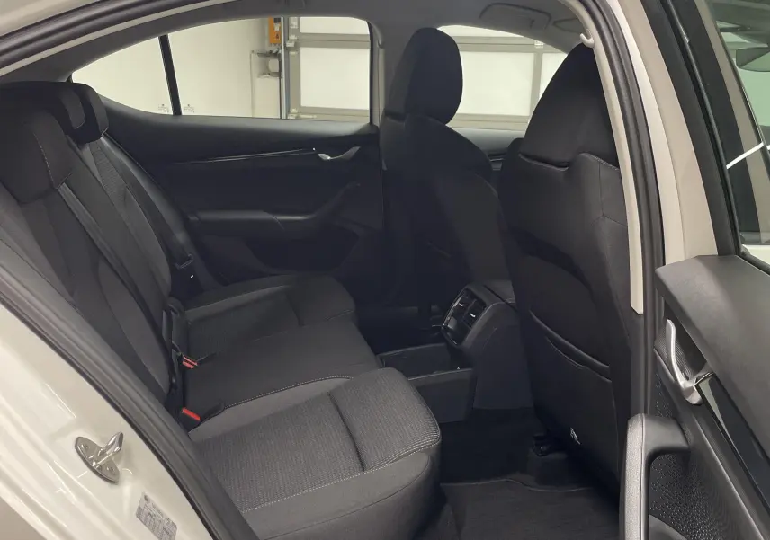 Intérieur arrière de la Skoda Octavia 2024 blanc candy, sièges noirs et porte arrière ouverte côté droit.