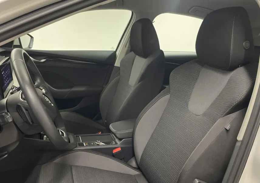 Vue intérieure côté conducteur de la Skoda Octavia 2024 blanc candy, sièges tissu gris et tableau de bord moderne.