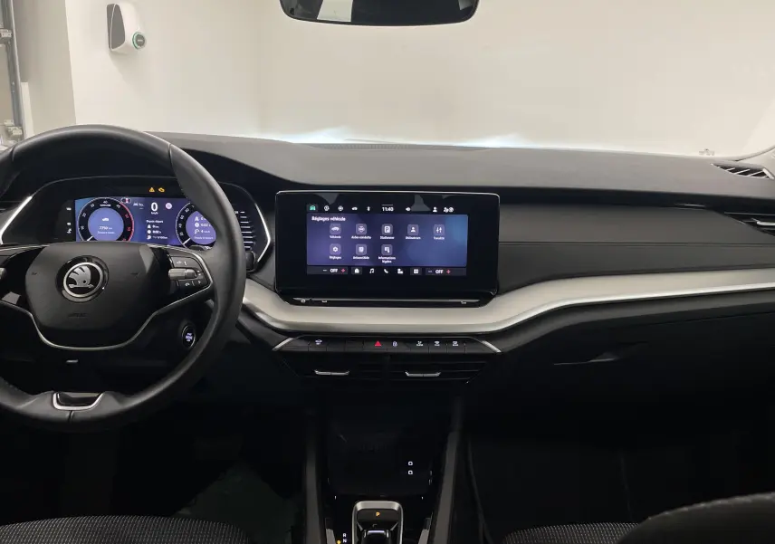 Intérieur de la Skoda Octavia 2024 blanc candy, vue frontale du tableau de bord avec écran tactile et volant multifonction.