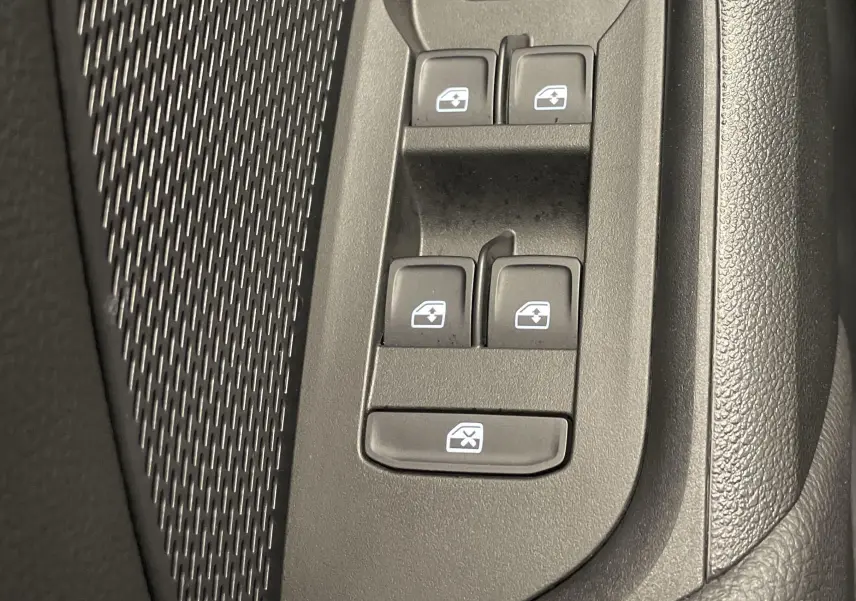 Gros plan sur les commandes des vitres électriques côté conducteur d'une Skoda Octavia 2024 blanc candy.