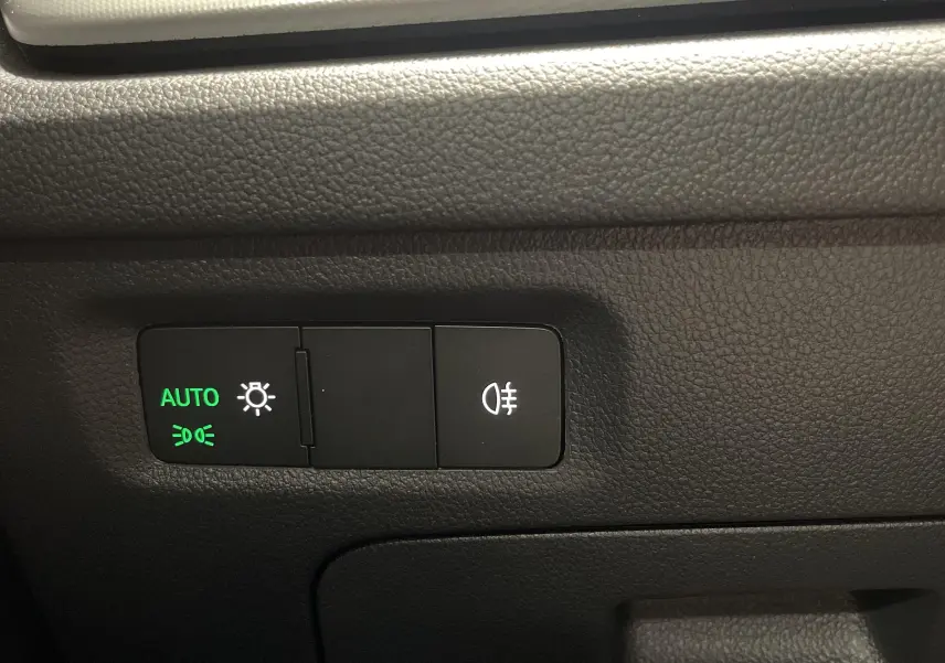 Boutons de commande des feux avec mode automatique activé, sur la planche de bord noire d'une Skoda Octavia 2024.