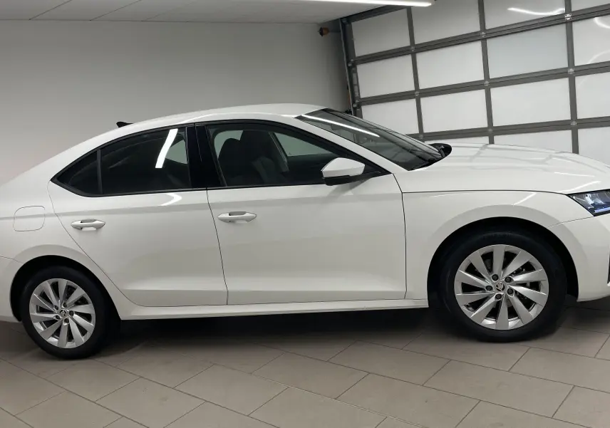 SKODA OCTAVIA 2024 blanc candy vue de profil côté gauche avec jantes alliage et feux arrière allumés.