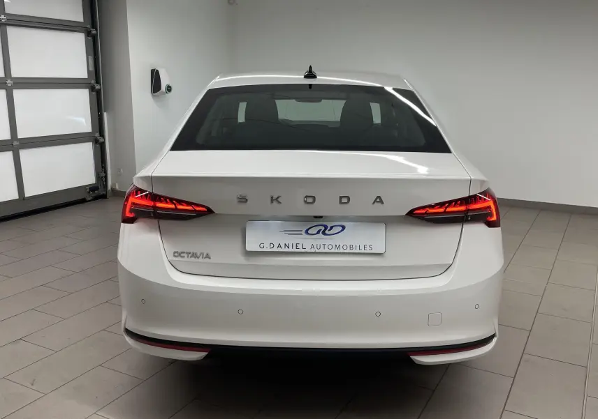 Vue arrière d'une Skoda Octavia blanche Candy 2024 avec feux LED allumés dans un garage intérieur.