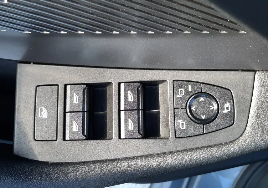 Panneau de commandes des vitres et rétroviseurs côté gauche dans une BMW Série 1 gris Skyscraper 2025.