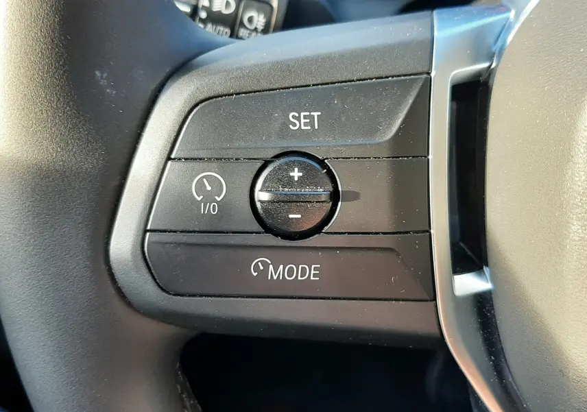 Gros plan sur les commandes de régulateur de vitesse au volant d'une BMW Série 1 120D M Sport Design 2025.