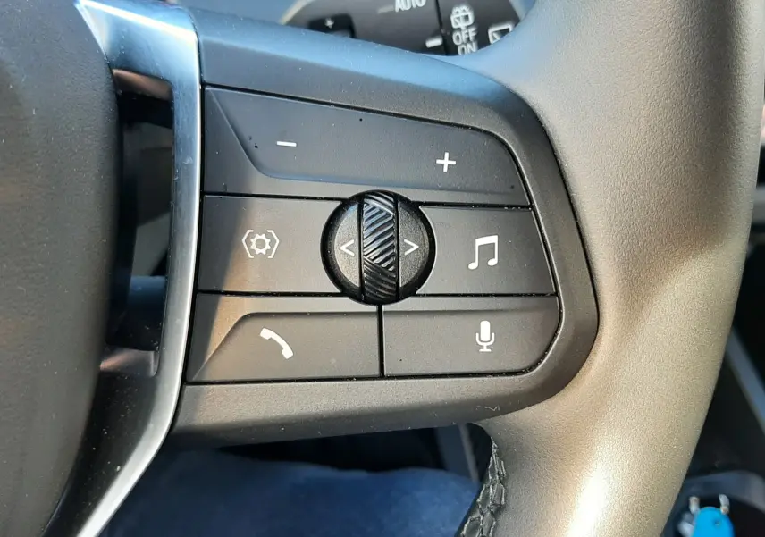 Gros plan sur les commandes multimédia à droite du volant gris d'une BMW Série 1 120D M Sport Design 2025.