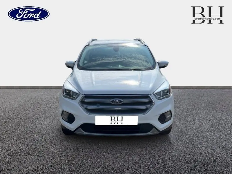 Vue frontale d'un Ford Kuga blanc glacier avec barres de toit aluminium et calandre distinctive.