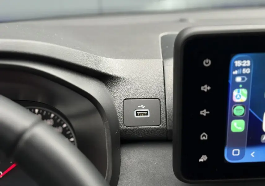 Gros plan sur la prise USB intégrée au tableau de bord du Dacia Sandero Stepway Bleu Iron, avec écran tactile visible.