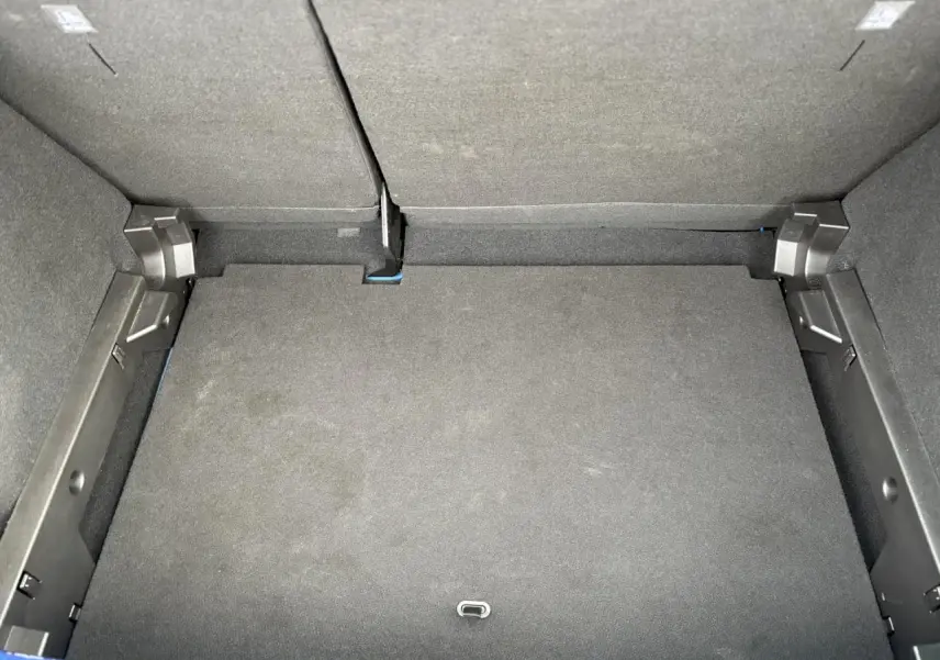 Coffre ouvert vu de dessus de la Dacia Sandero Stepway Bleu Iron, montrant l'espace de chargement vide et les dossiers arrière rabattus.