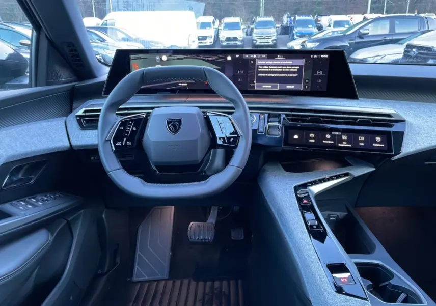 Vue intérieure du poste de conduite du Peugeot 5008 Hybrid 145 Allure Plus 2025, avec volant cuir multifonctions et écran panoramique incurvé.