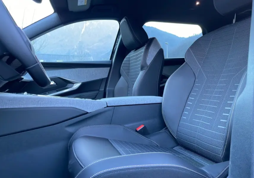 Vue intérieure côté droit montrant les sièges avant en cuir tissu gris avec surpiqûres contrastées du Peugeot 5008 Hybrid 2025.