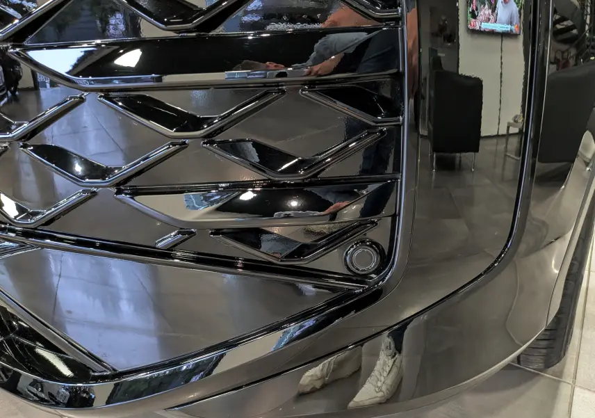 Gros plan sur la calandre noire brillante du Volkswagen T-Roc eTSI 150 CH DSG7 R-Line 2026, soulignant son design géométrique.